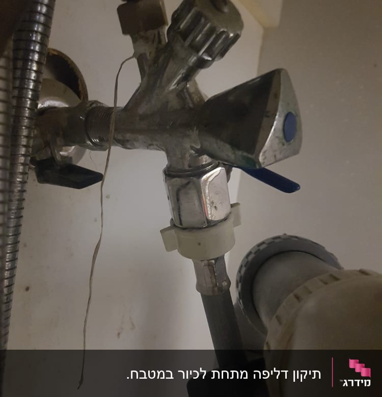 ברזים וצינורות מתכת מתחת לכיור